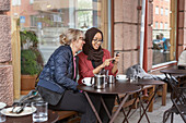 Frauen sitzen in einem Café im Freien zusammen