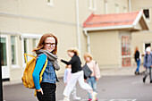 Lächelndes Mädchen vor einem Schulgebäude