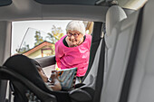 Grandmother looking at baby girl sitting inside car