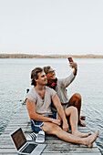 Mutter mit erwachsenem Sohn auf dem Bootssteg beim Selfie machen