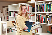 Bibliothekarin stellt Bücher ins Regal