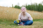 Smiling girl on meadow holding wildflowers