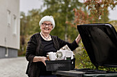 Lächelnde ältere Frau trägt Recycling-Müll