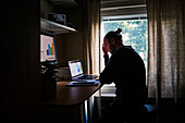Silhouette eines Mannes, der zu Hause einen Laptop benutzt