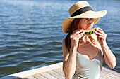 Frau auf Bootssteg isst Wassermelone