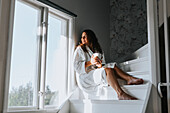 Woman sitting on stairs and looking through window