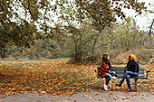 Freundinnen unterhalten sich auf einer Bank im Park