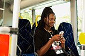 Junge Frau benutzt Handy im Bus