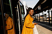 Smiling woman leaving bus at bus station