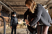 Mutter mit Tochter bereitet Pony für Ausritt vor