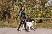 Sehbehinderte Frau geht mit Blindenhund spazieren