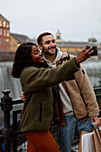 Young couple taking selfie near canal in town