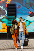 Junges Paar geht mit Gepäck auf der Straße spazieren