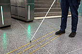 Niedriger Ausschnitt einer Person mit weißem Stock, die an einer U-Bahn-Station steht