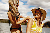 Woman applying sun cream on friends back