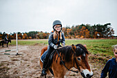 Smiling girl riding pony