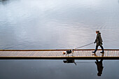 Frau mit Beagle-Hund geht auf Steg spazieren