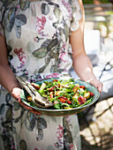 Mittelteil einer Frau mit einem Teller mit Salat