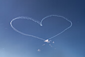 Low angle view of vapor trail heart shaped