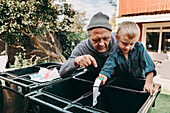 Vater und Sohn beim Abfallrecycling im Garten