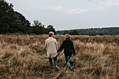 Female couple walking through meadow