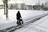 Ältere Frau mit Gehhilfe bei einem Winterspaziergang