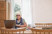 Ältere Frau mit Laptop am Tisch