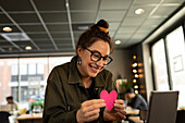Smiling woman in cafe holding paper heart