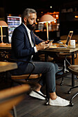 Businessman using cell phone in cafe