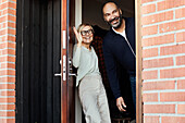 Smiling mature couple at front door