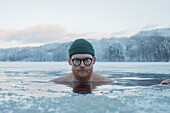 Man swimming in frozen lake