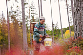 Senior woman in autumn forest picking berries