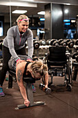 Frau trainiert im Fitnessstudio mit Personal Trainer