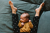 Baby schläft zwischen den Beinen eines Geschwisters aus hohem Winkel