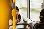 Junge Frau im Bus, die ein Mobiltelefon benutzt