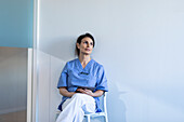 Krankenschwester sitzt auf einem Stuhl und hält ein Tablet in der Hand