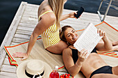 Lächelnde Frauen in Badeanzügen entspannen sich am See