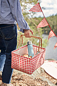Woman holding picnic basket with food and drink