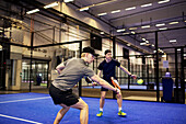 Men playing doubles padel at indoor court