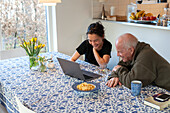 Young woman with grandfather using laptop