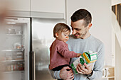 Father carrying toddler daughter in kitchen