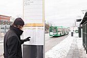 Young man checking timetable at bus stop