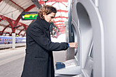 Mann benutzt Fahrkartenautomat im Bahnhof