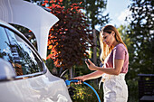 Frau lädt Elektroauto auf