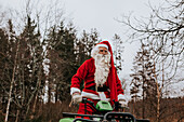 Man wearing Santa costume riding lawn mower