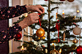 Frauenhände beim Schmücken des Weihnachtsbaums