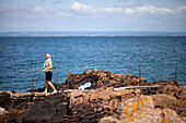 Senior man walking on rocky sea shore