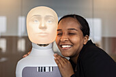 Lächelnde junge Frau mit Roboter-Sprachassistent