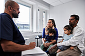 Männlicher Arzt im Gespräch mit einer Familie mit Kindern