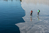 People ice-skating near open sea